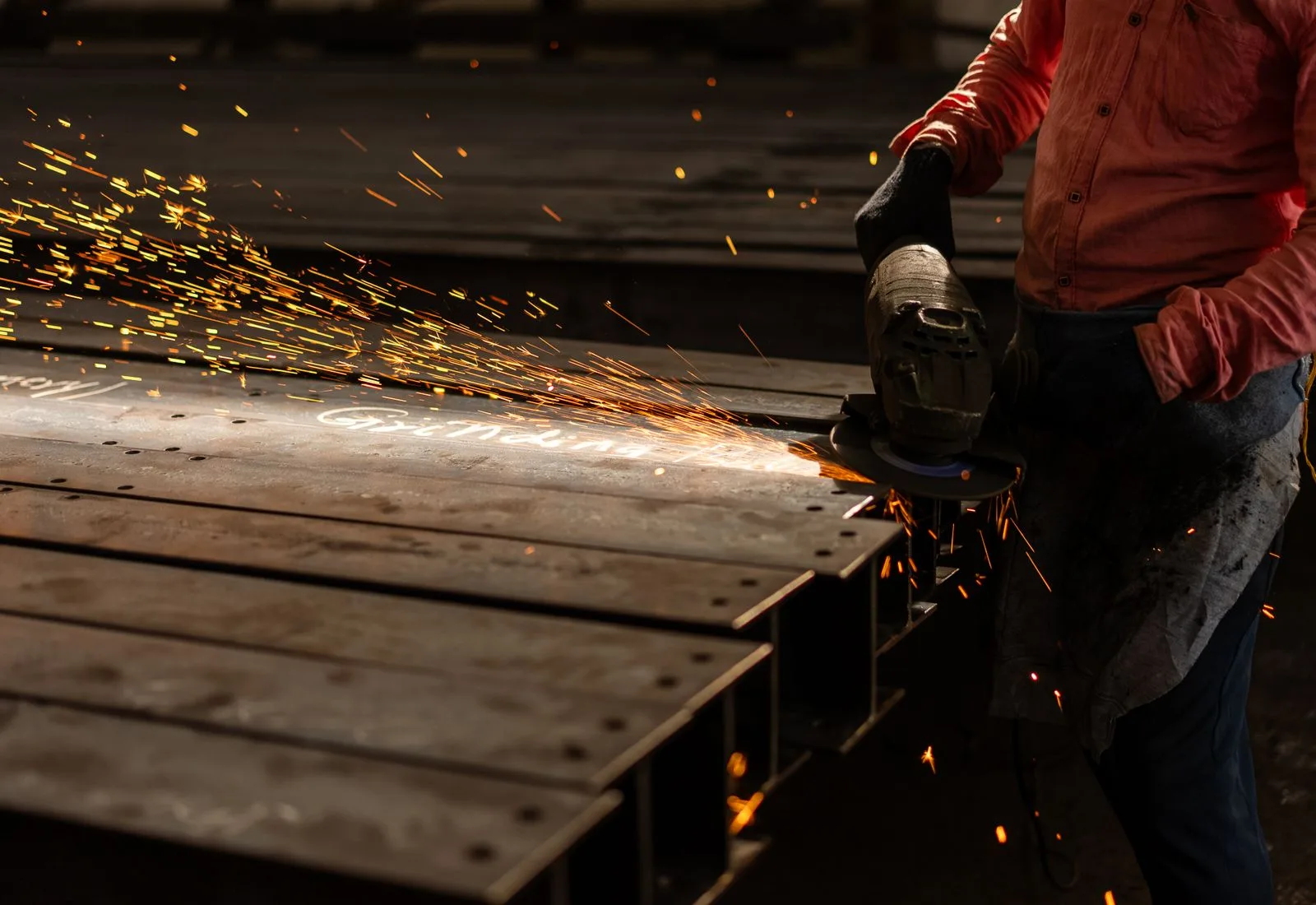 Metal fabricator grinding steel with sparks